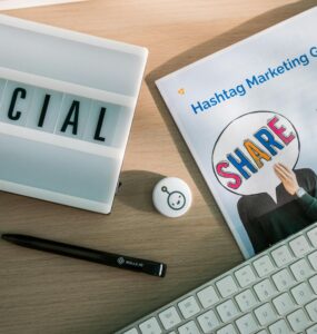 A desktop setup with social media marketing essentials including a keyboard, lightbox, and guide.