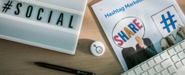 A desktop setup with social media marketing essentials including a keyboard, lightbox, and guide.