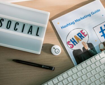 A desktop setup with social media marketing essentials including a keyboard, lightbox, and guide.