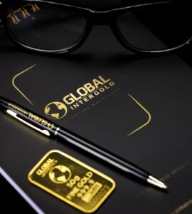 An elegant setup with a notebook, pen, and gold bar, embodying luxury and style.