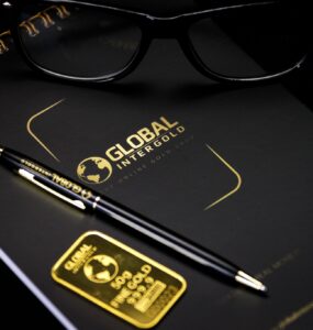 An elegant setup with a notebook, pen, and gold bar, embodying luxury and style.