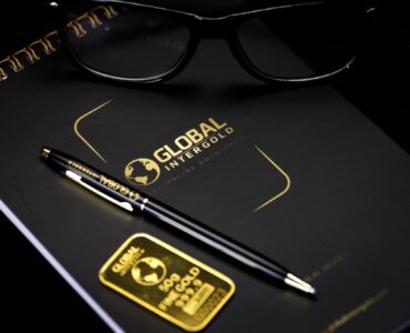 An elegant setup with a notebook, pen, and gold bar, embodying luxury and style.